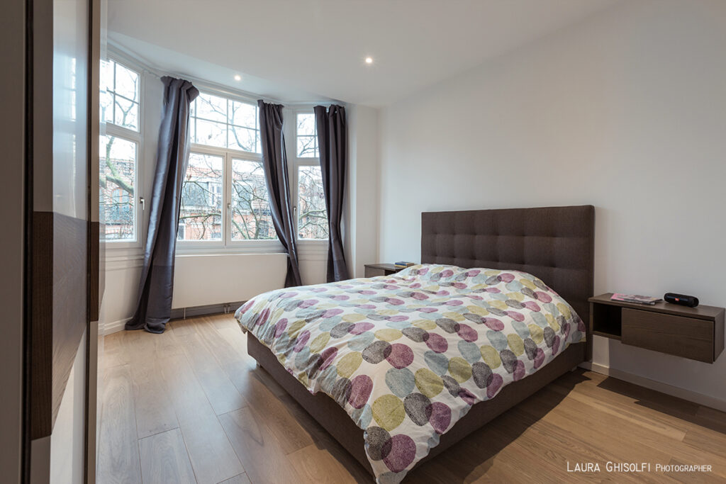 Ampio letto con testata imbottita che richiama le tonalità del legno usato per i comodini